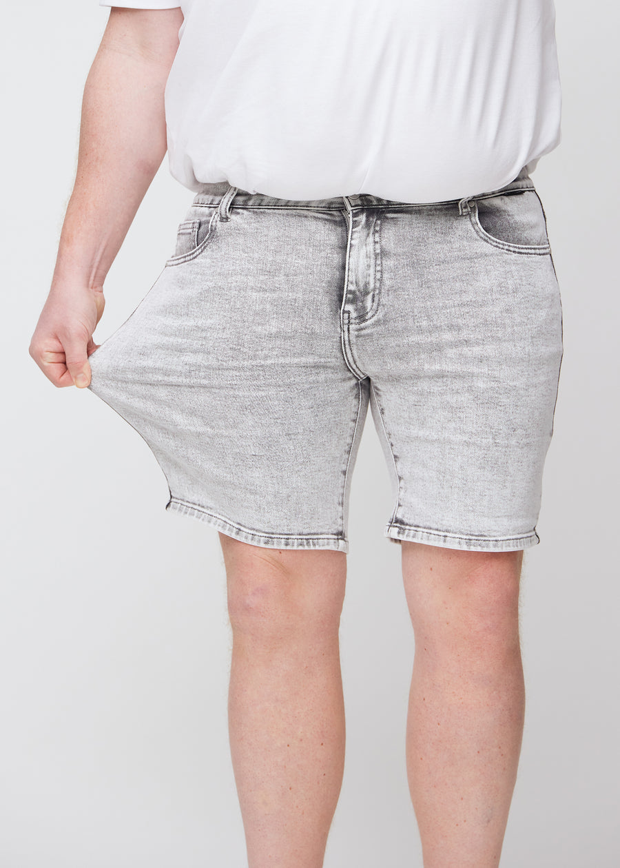 Plus-size model strækker shortsene ved låret for at vise stretch.