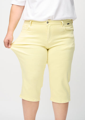 Plus-size model strækker caprisene ved låret for at vise stretch.