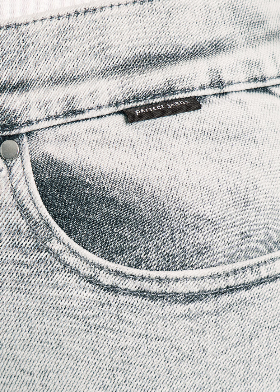 Nærbillede af lysegrå denim med Perfect Jeans logoetiket ved forlommekanten.
