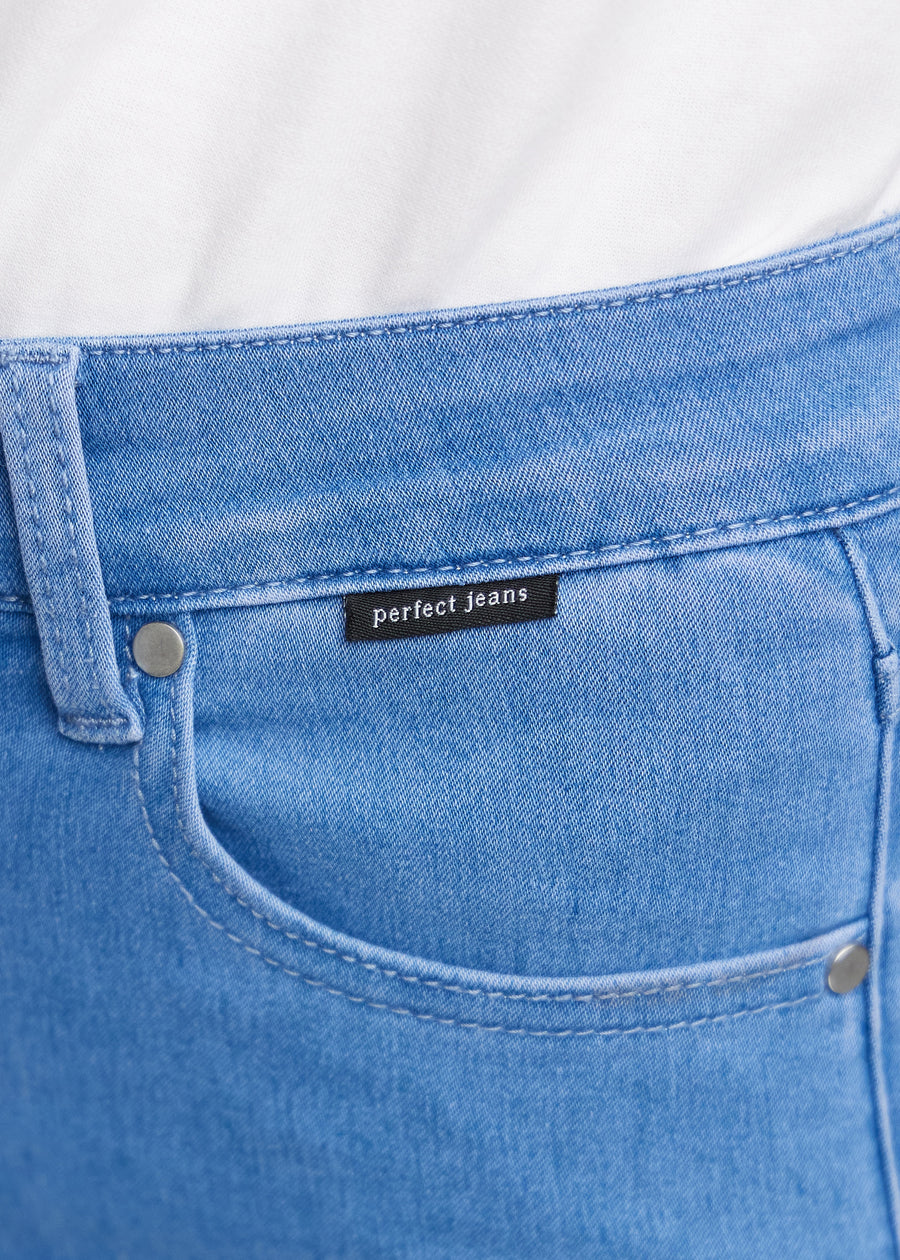 Nærbillede af blåt jeansmateriale med Perfect Jeans logoetiket ved forlommekanten.
