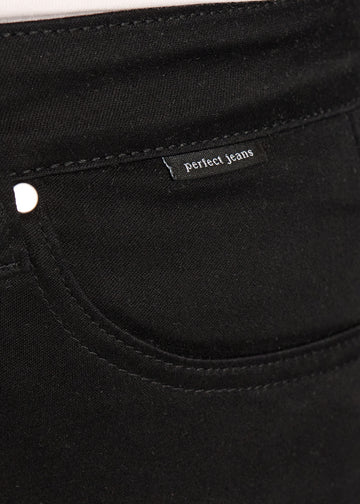 Nærbillede af sort jeansmateriale med Perfect Jeans logoetiket ved forlommekanten, på en plus-size model.