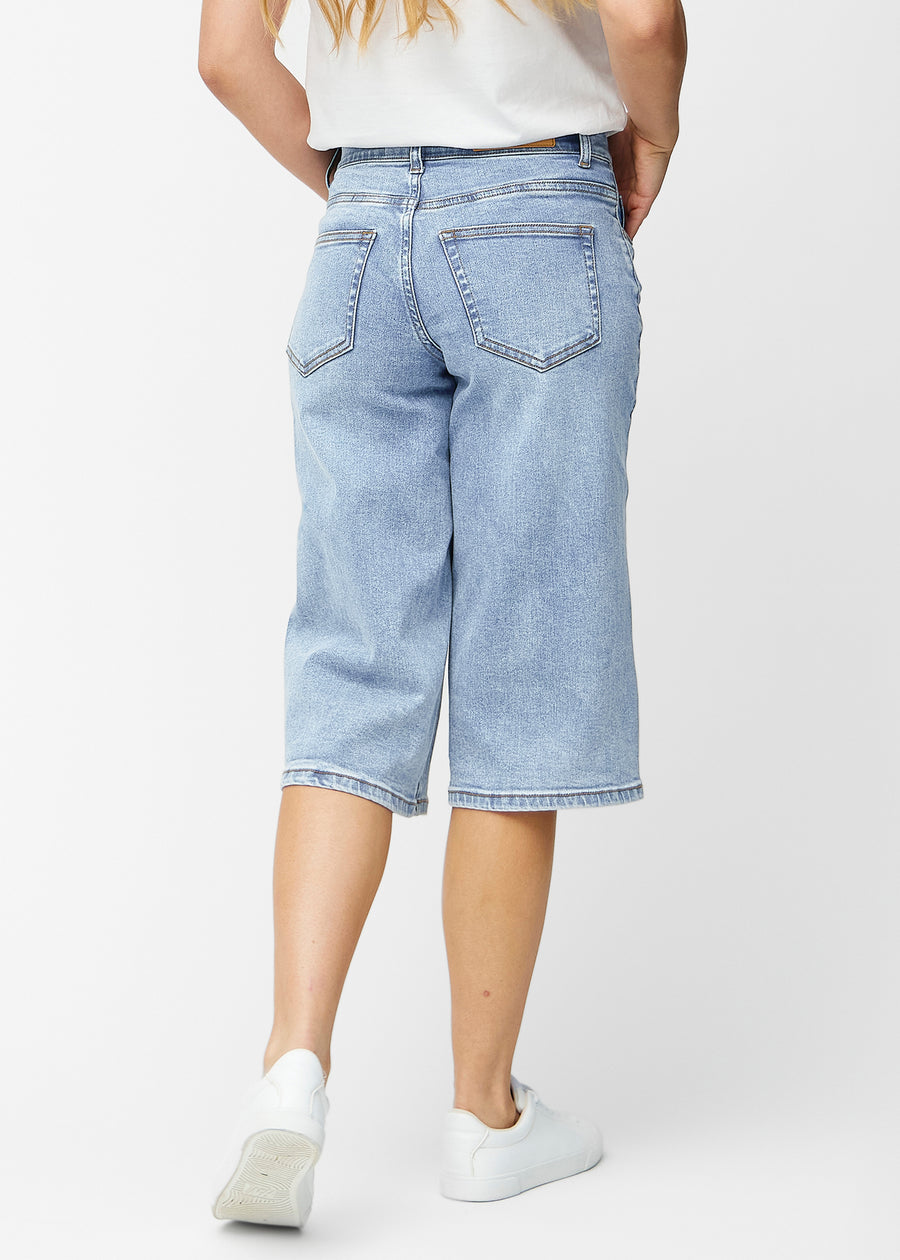Lösa, ljusblå denim capris i färgen Waves sedda bakifrån, så att passform och längd syns.