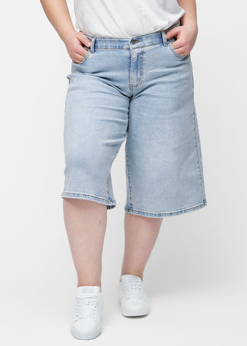 Lösa, ljusblå denim capris i färgen Waves sedda framifrån på plus-size modell, som sitter vid höften och faller löst.