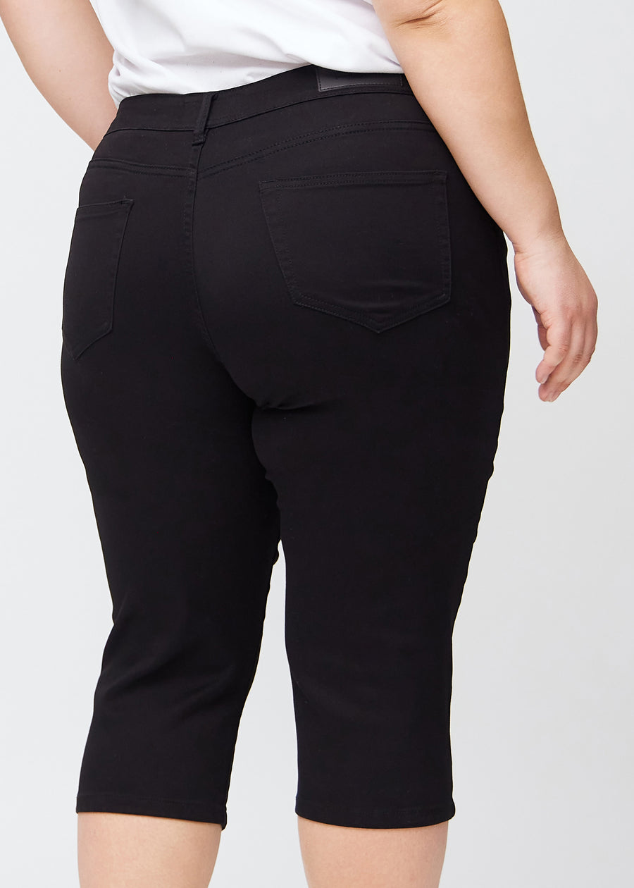 Tæt billede af bagdelen på en plus-size model i sorte slim capris – detaljefokus på lommer og syninger.