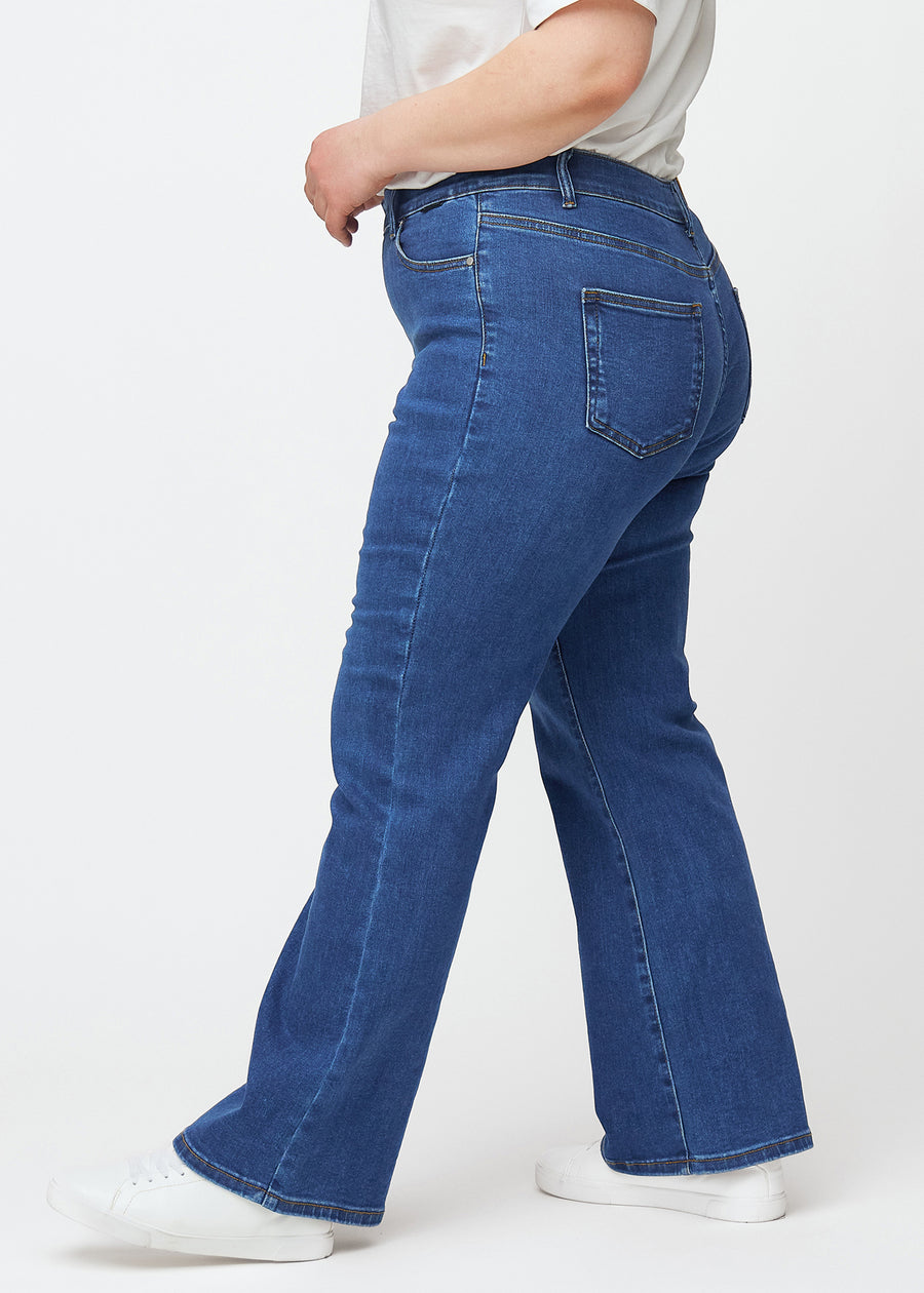 Mörkblå mid-rise bootcutjeans i färgen Oceans. Från sidan på en plus size-modell.