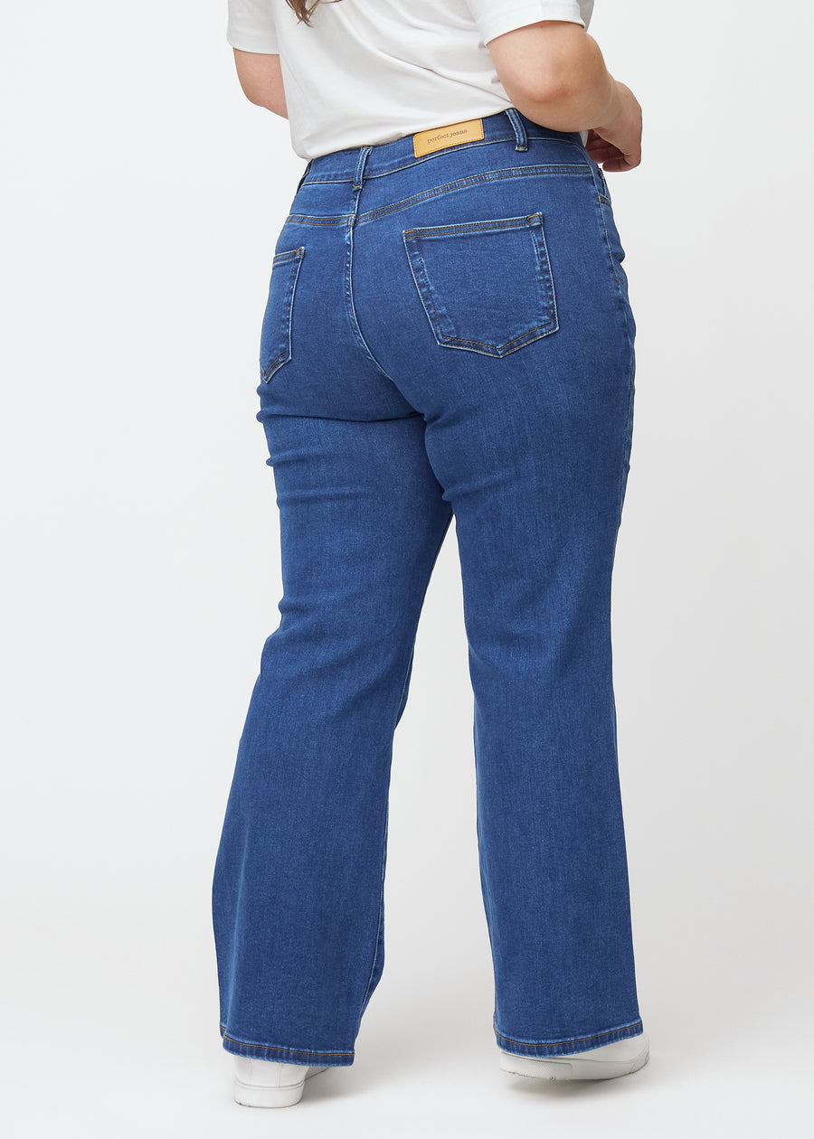 Mörkblå mid-rise bootcutjeans i färgen Oceans. Bakifrån på en plus size-modell, så att hela passformen syns.