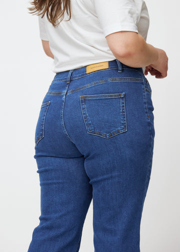 Mörkblå mid-rise bootcutjeans i färgen Oceans. Närbild bakifrån på en plus size-modell som visar detaljerna.