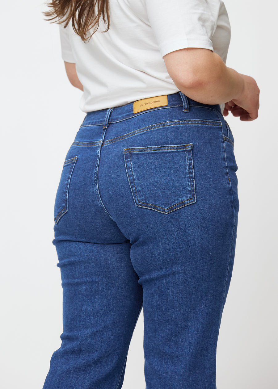 Mörkblå mid-rise bootcutjeans i färgen Oceans. Närbild bakifrån på en plus size-modell som visar detaljerna.