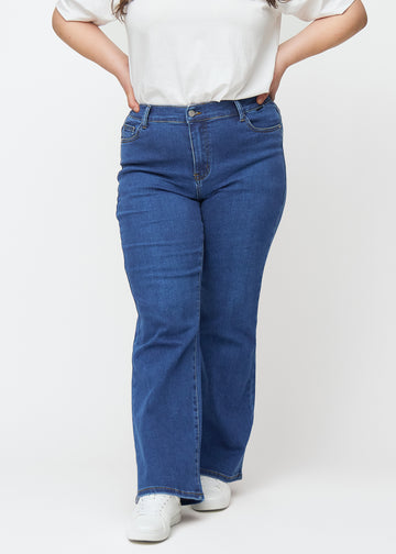 Mörkblå mid-rise bootcutjeans i färgen Oceans. Framifrån på en plus size-modell, med nära passform över höfter och lår och lätt utsvängning nedtill.