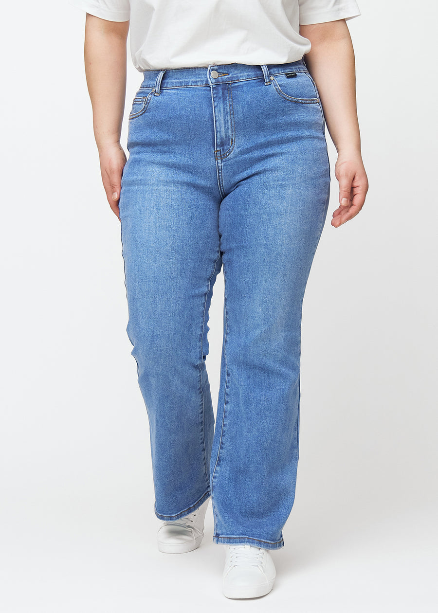 Blå mid-rise bootcutjeans i färgen Rivers. Framifrån på en plus size-modell, med nära passform över höfter och lår och lätt utsvängning nedtill.