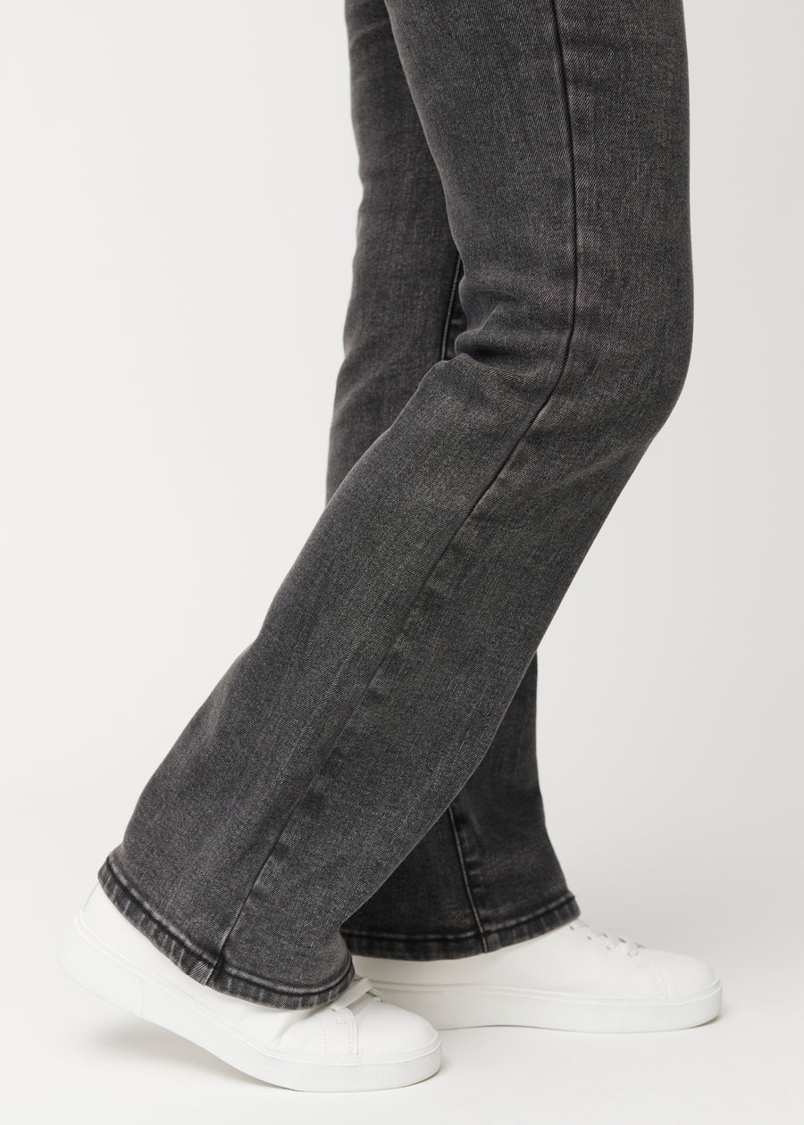 Mörkgrå mid-rise bootcutjeans i färgen Shadows. Närbild vid ankeln på en modell som visar den lätta utsvängningen nedtill.