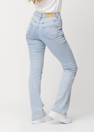 Ljusblå mid-rise bootcutjeans i färgen Waves. Bakifrån på en modell, så att hela passformen syns.