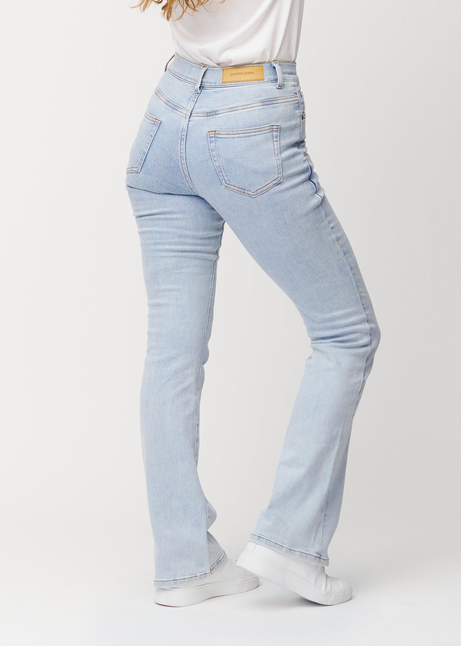 Ljusblå mid-rise bootcutjeans i färgen Waves. Bakifrån på en modell, så att hela passformen syns.