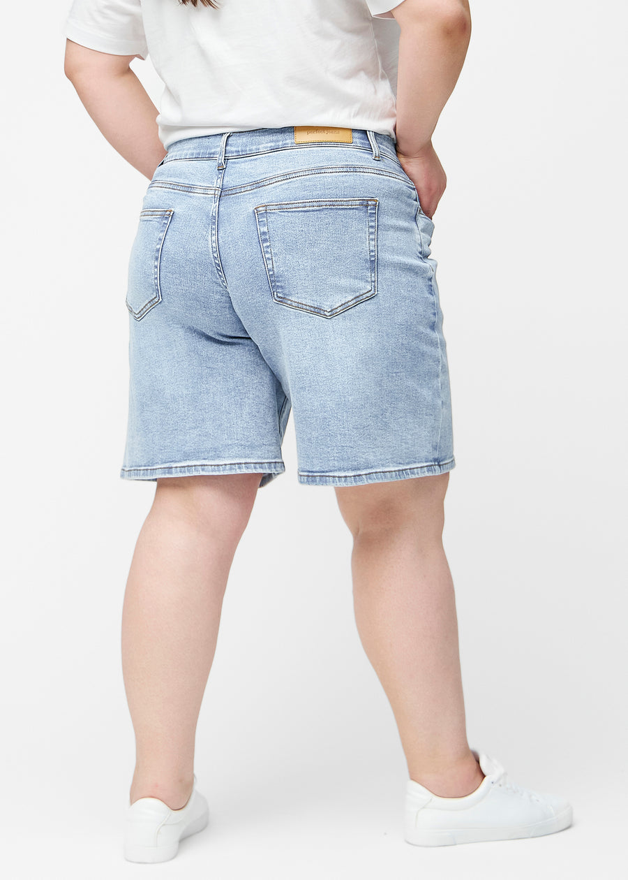 Lösa, ljusblå denimshorts i färgen Waves sedda bakifrån på plus-size modell, så att passform och längd syns.