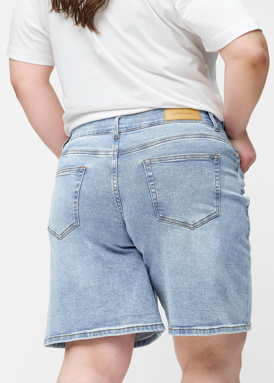 Lösa, ljusblå denimshorts i färgen Waves sedda bakifrån på nära håll på plus-size modell för att visa passform och detaljer.