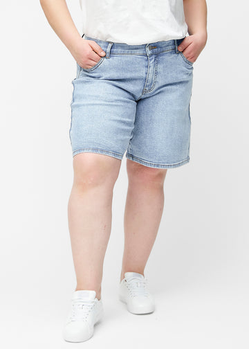 Lösa, ljusblå denimshorts i färgen Waves sedda framifrån på plus-size modell, som sitter vid höften och faller löst.