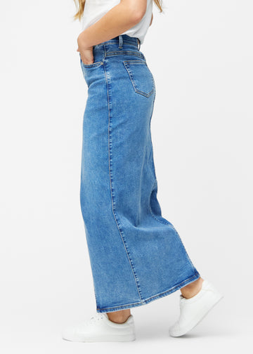 Lang, klassisk blå denimnederdel i farven Rivers med regulær pasform set fra siden på model, med synligt slids foran.