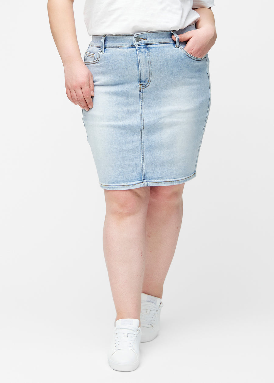 Lyseblå, tætsiddende og knælang denimnederdel set forfra på plus-size model.