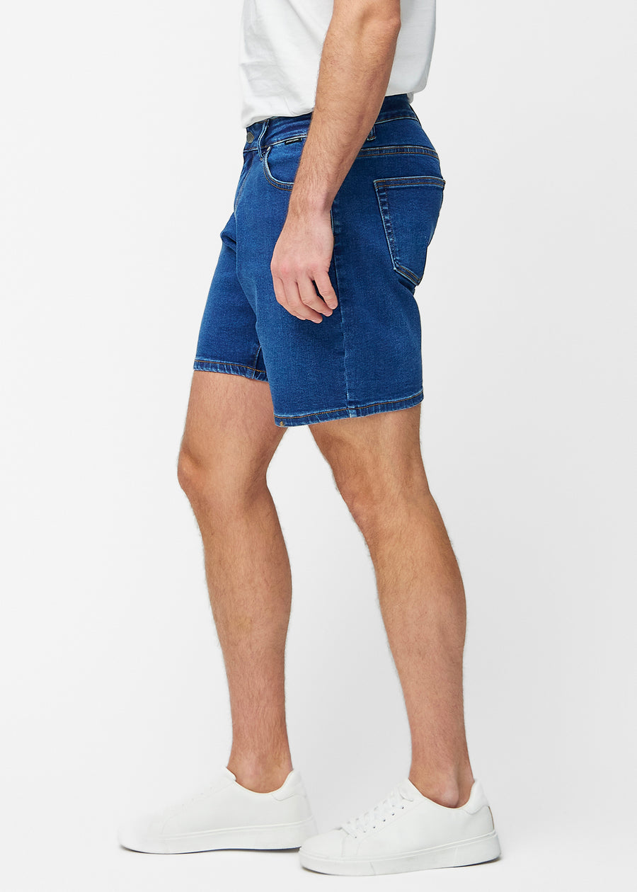 Mörkblå denimshorts för herr i färgen Oceans med regular passform sett från sidan på modell.