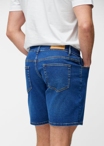 Mörkblå denimshorts för herr i färgen Oceans sett bakifrån så att längden till precis över knät och passformen kan ses.
