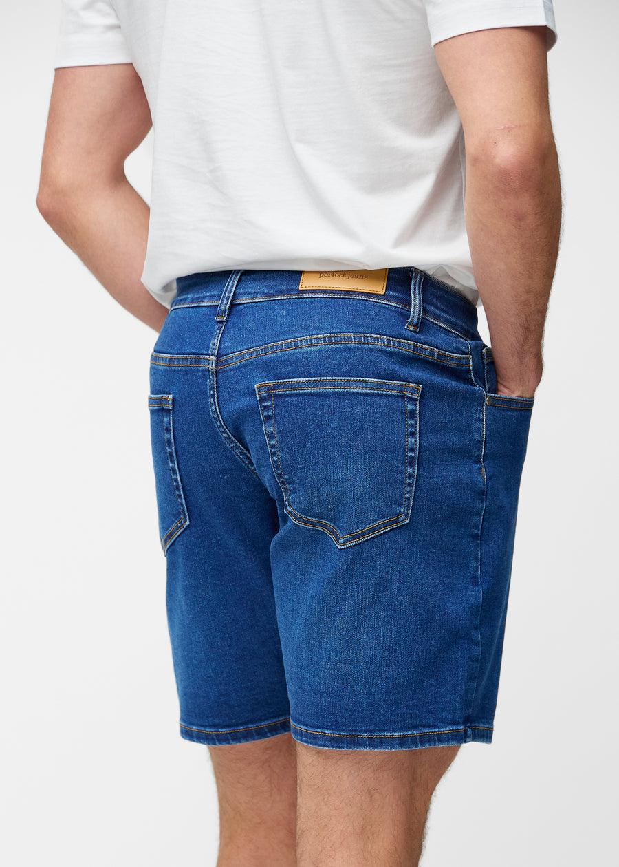 Mörkblå denimshorts för herr i färgen Oceans sett bakifrån så att längden till precis över knät och passformen kan ses.