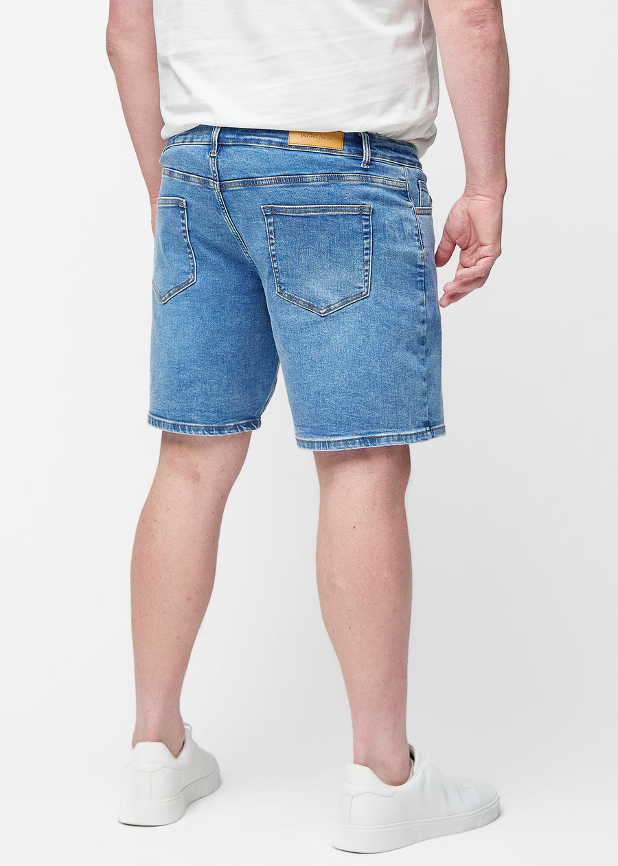Blå denimshorts för herr i färgen Rivers sett bakifrån på plus-size modell så att längden till precis över knät kan ses.