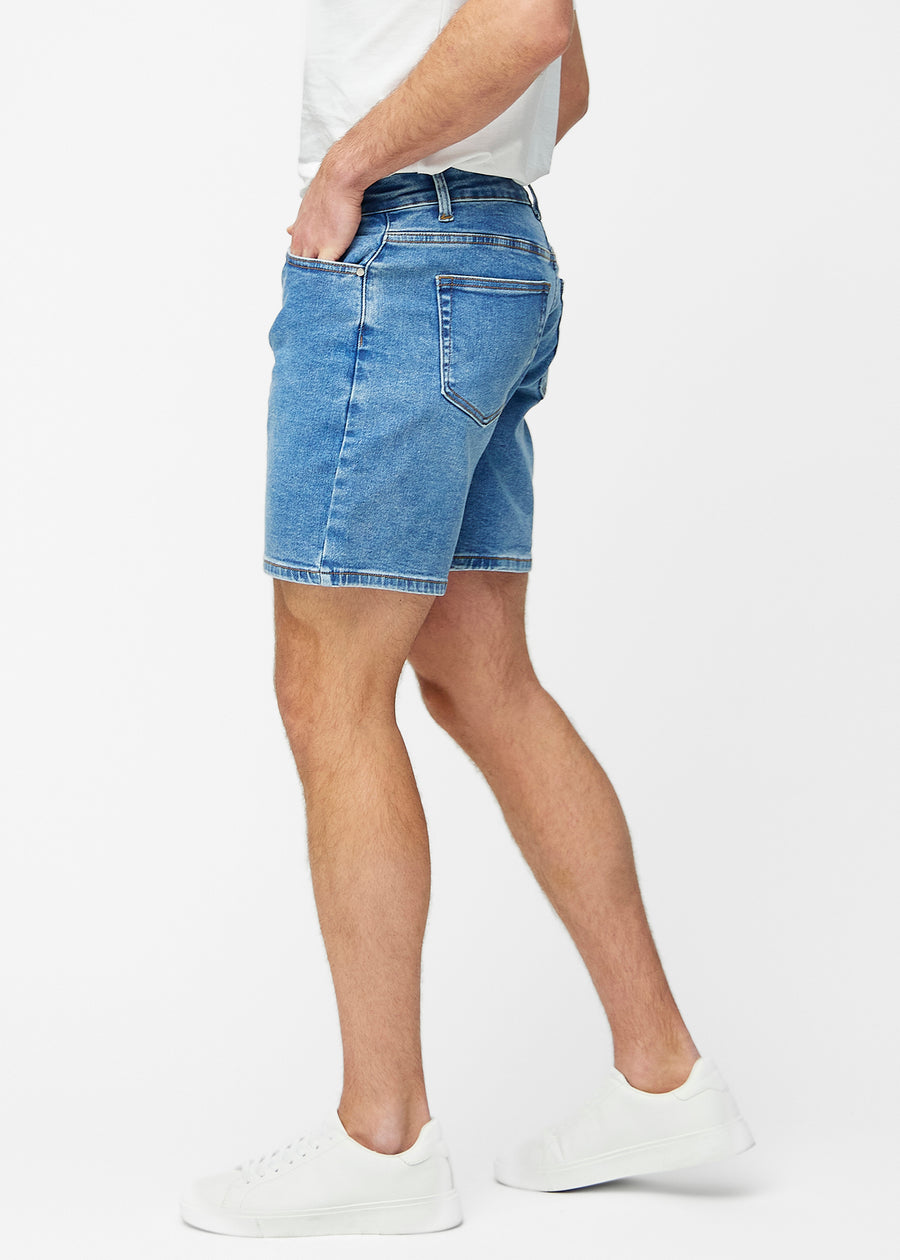 Blå denimshorts för herr i färgen Rivers med regular passform sett från sidan på modell.