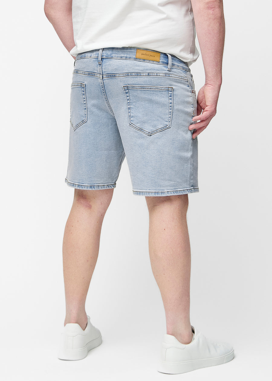 Ljusblå denimshorts för herr i färgen Waves sett bakifrån på plus-size modell, så att längden till precis över knät kan ses.
