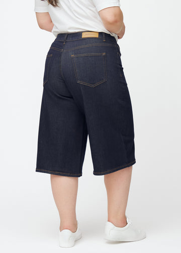 Mörkblå denim capris för dam i färgen Midnights sett bakifrån på plus-size modell.