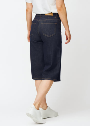 Mörkblå denim capris för dam i färgen Midnights sett bakifrån, där längden under knät syns.