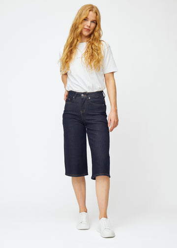 Helbild av modell i mörkblå denim capris för dam i färgen Midnights med loose passform.