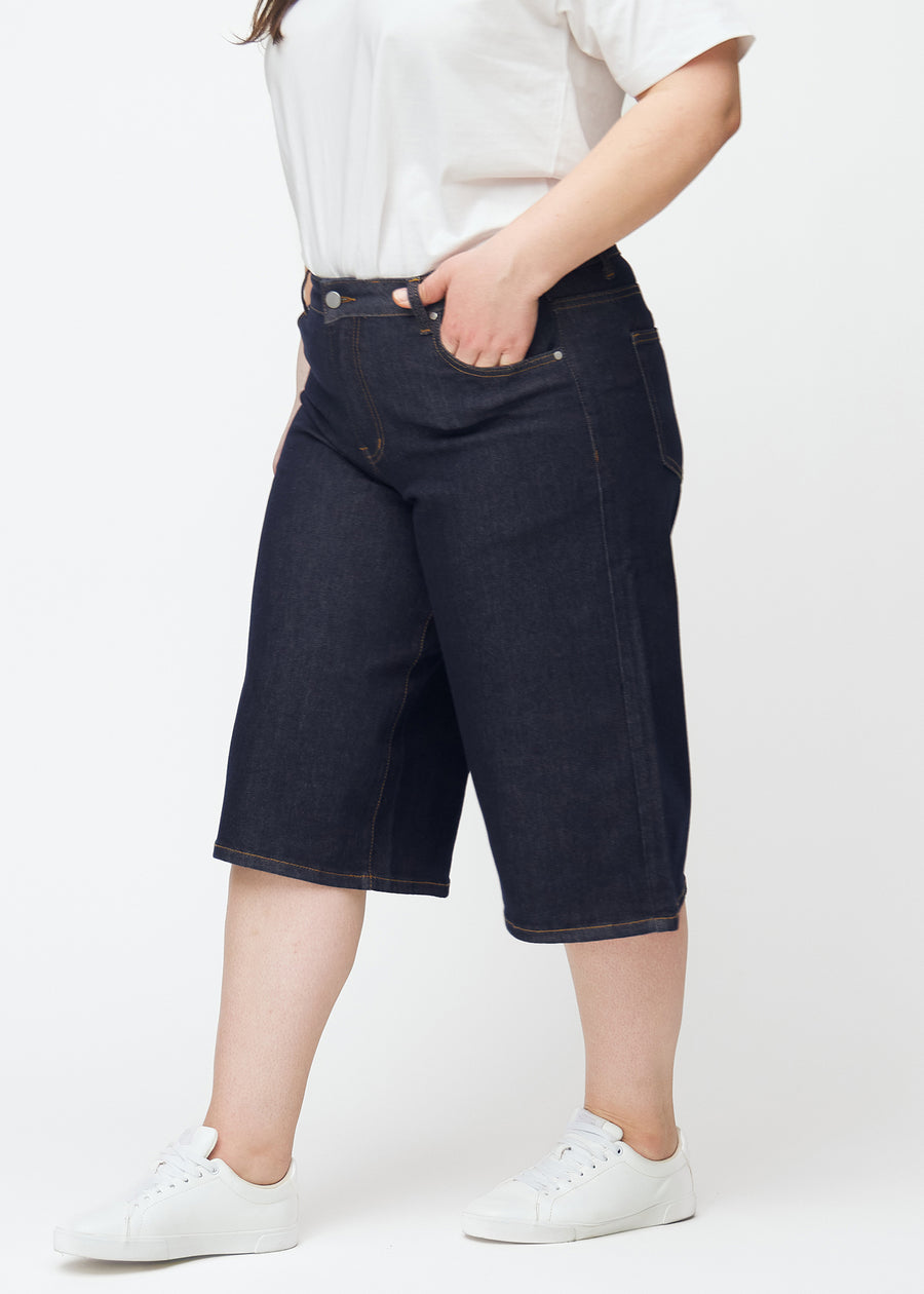 Mörkblå denim capris för dam i färgen Midnights med loose passform sett från sidan på plus-size modell.
