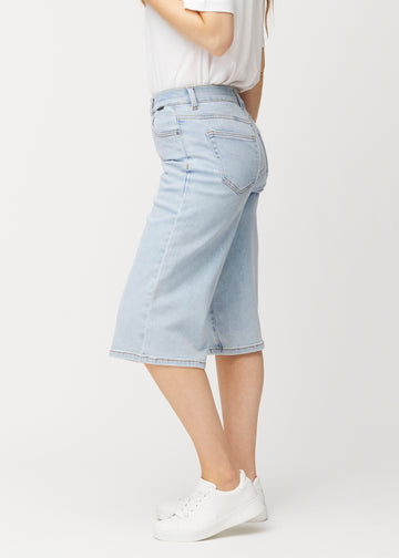 Lösa, ljusblå Waves denimcapribyxor sedda från sidan på en modell, som visar den vida passformen och längden till strax nedanför knät.