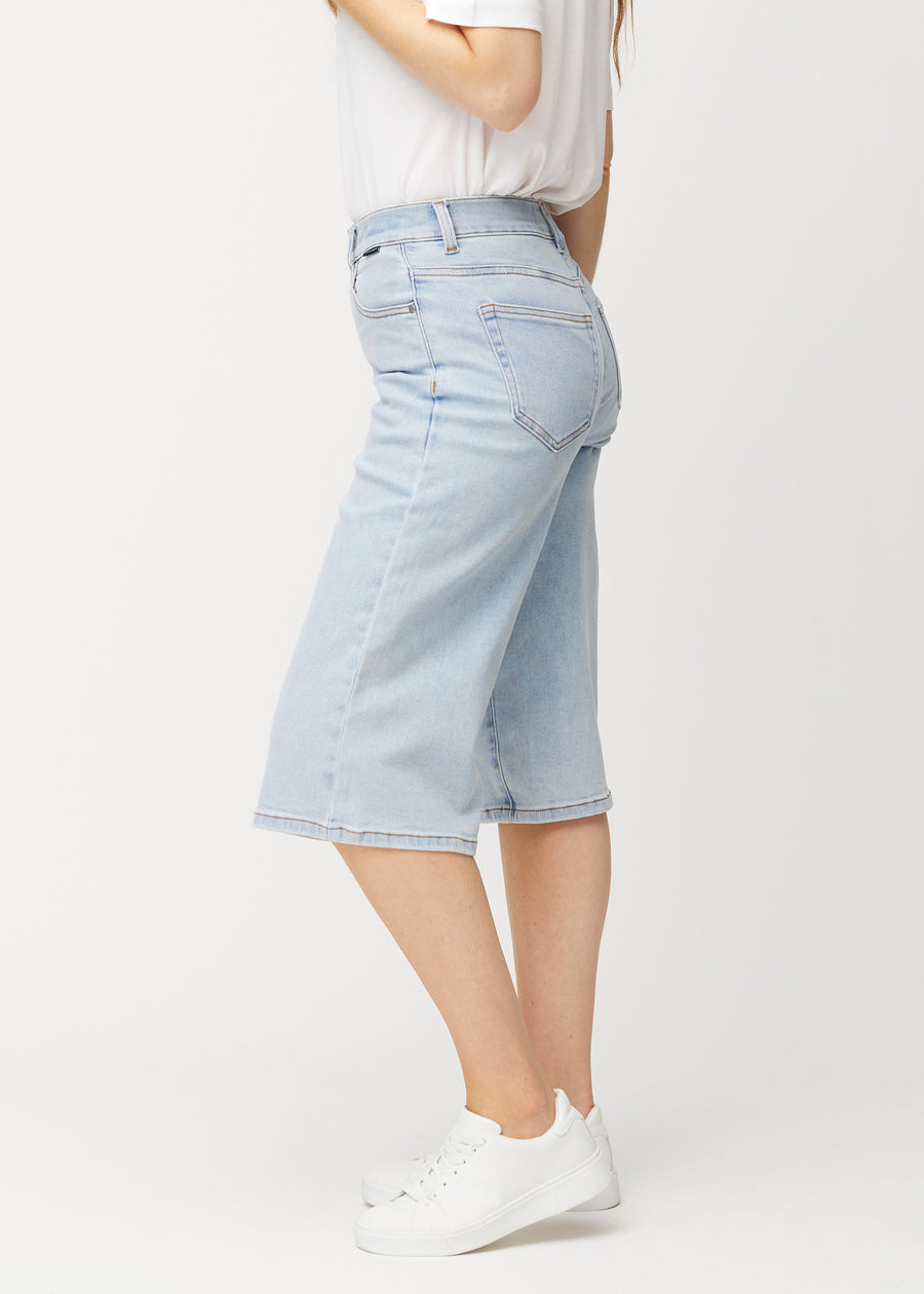 Lösa, ljusblå Waves denimcapribyxor sedda från sidan på en modell, som visar den vida passformen och längden till strax nedanför knät.