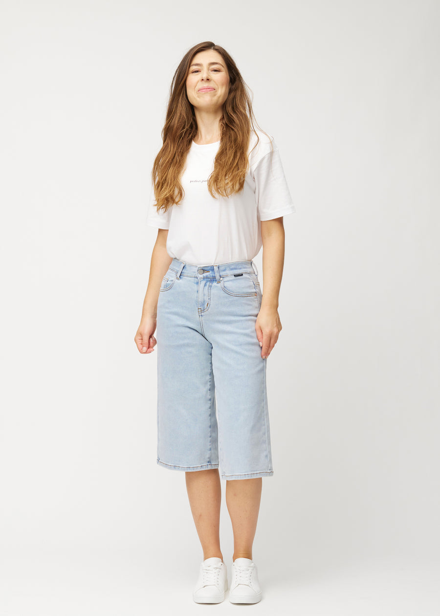 Helbild av en modell i lösa, ljusblå Waves denimcapribyxor som slutar strax nedanför knät.