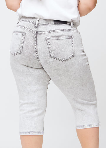 Ljusgrå denim regular capris sedda bakifrån på nära håll på en plus-size-modell för att visa detaljer.