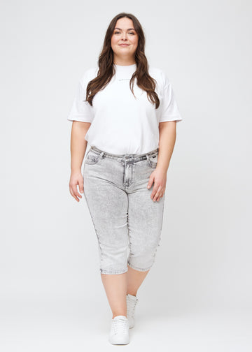 Helbild av en plus-size-modell i ljusgrå denim regular capris.