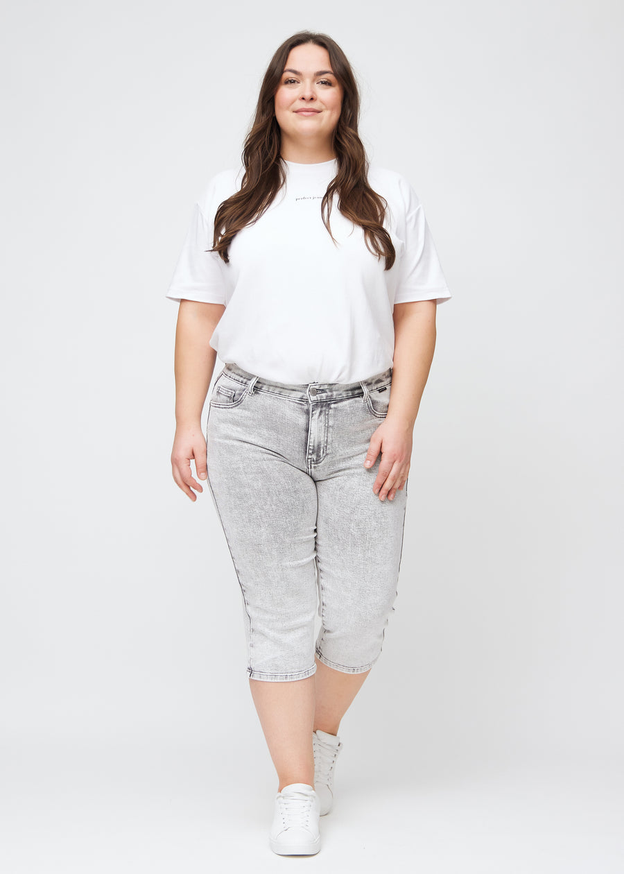 Helbild av en plus-size-modell i ljusgrå denim regular capris.