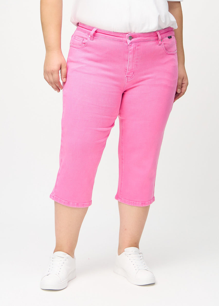 Ljusrosa regular capris, modellnamn Flamingos, som går rakt ner längs benet på en plus size-modell, framifrån.