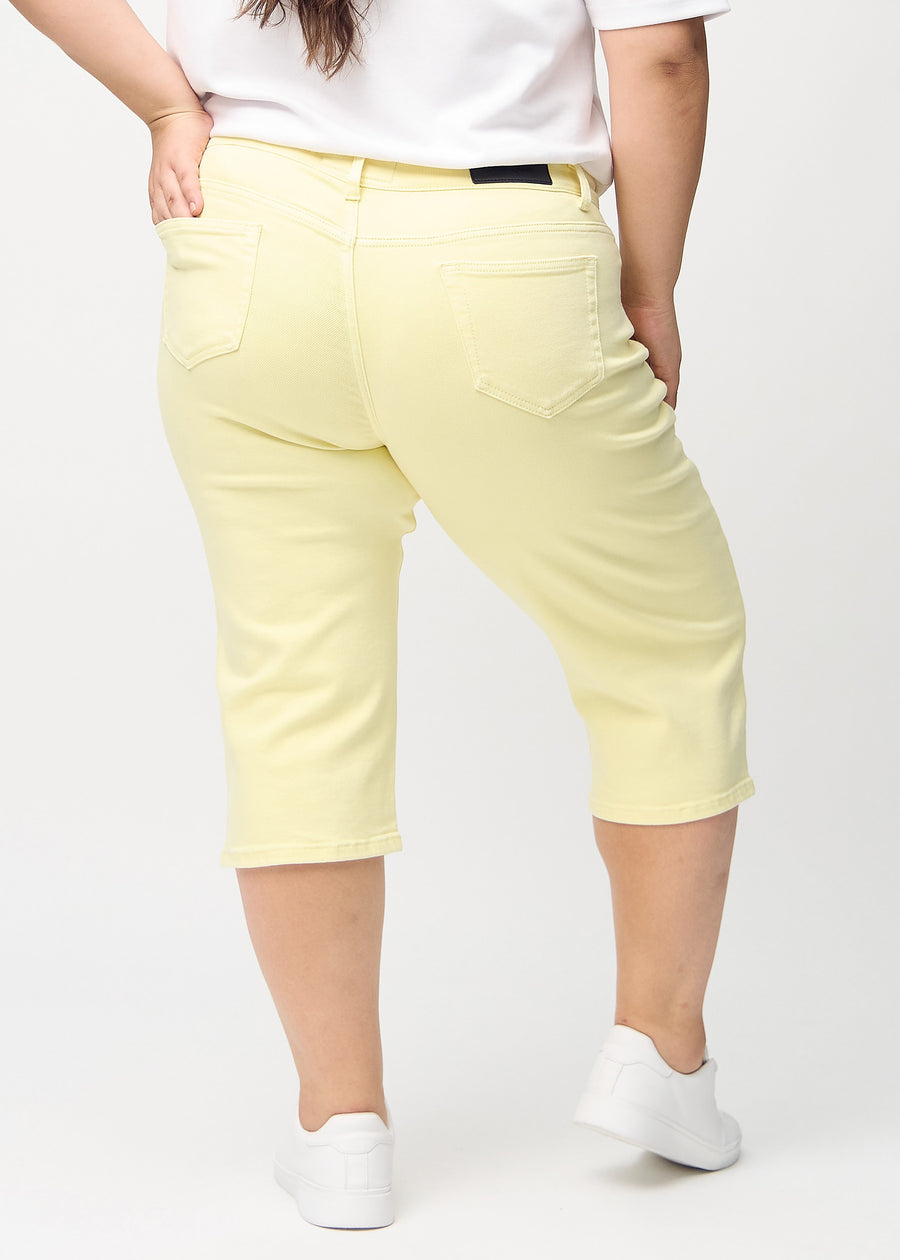 Ljusgula regular capris sedda bakifrån på en plus size-modell, så att man kan se hela produkten.