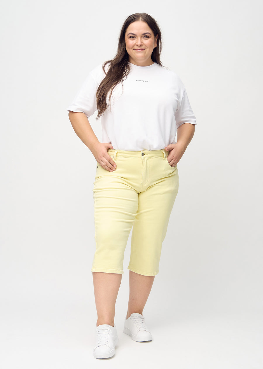 Ljusgula regular capris sedda bakifrån i närbild på en plus size-modell för att visa detaljer.