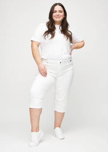 Helbild av en plus size-modell i vita regular capris.