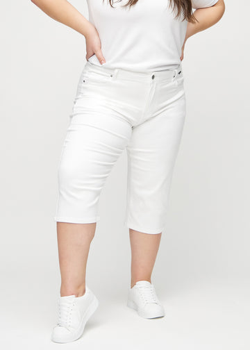 Vita regular capris, modellnamn Marguerites, som sitter rakt längs benet och slutar precis under knät på en plus size-modell, sedda framifrån.