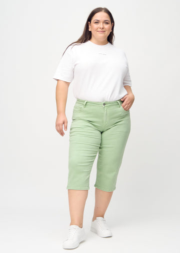 Helbild av en plus-size-modell i ljusgröna regular capris.