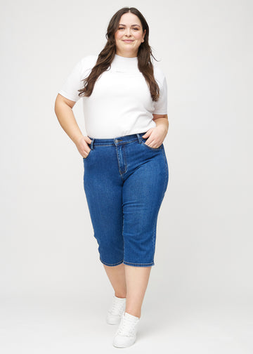 Helbild av en plus size-modell i mörk denim regular capris.