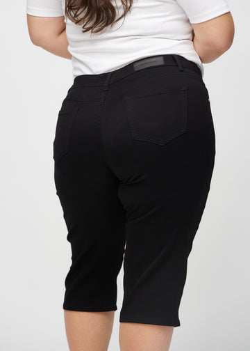Svarta regular capris sett bakifrån på nära håll på en plus-size-modell för att visa detaljer.