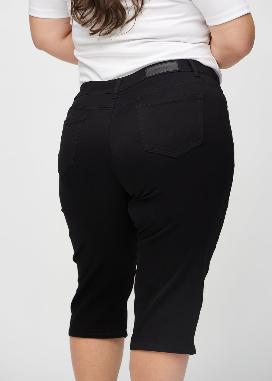 Svarta regular capris sett bakifrån på nära håll på en plus-size-modell för att visa detaljer.