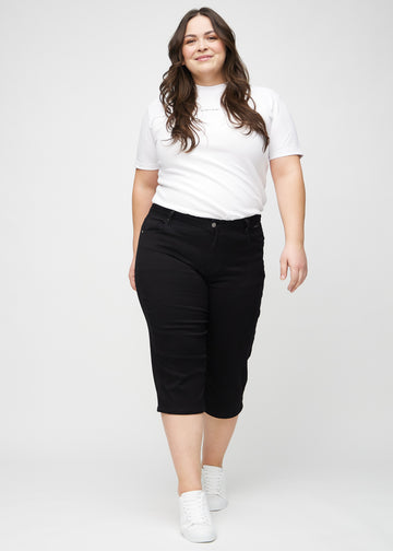 Helbild av en plus-size-modell i svarta regular capris.