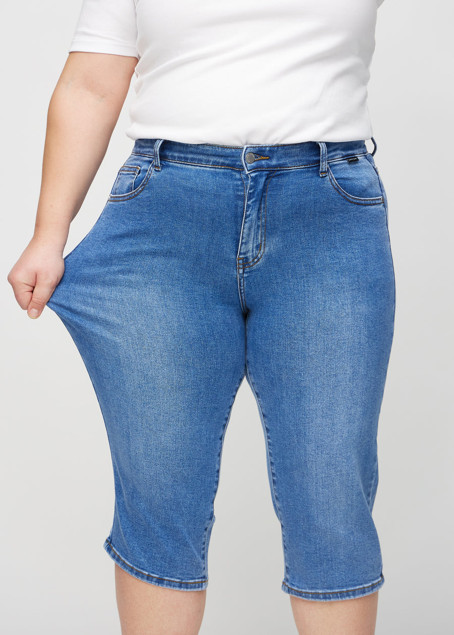 Plus size-modellen sträcker caprisen vid låret för att visa stretch.