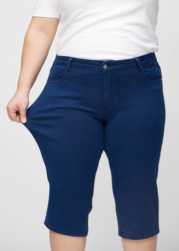 Plus size-modellen stretchar caprisen vid låret för att visa stretch.